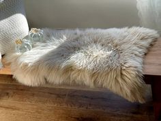 a white sheepskin rug sitting on top of a wooden bench next to a window