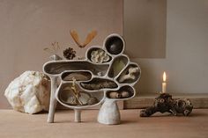 a sculpture made out of various objects on a table next to a candle and some rocks