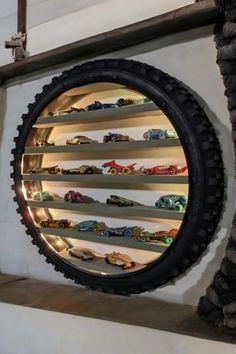 there are many toy cars on the shelves in this display case that is made to look like a tire