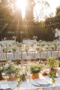 an outdoor table set up with place settings and greenery on it for a wedding reception