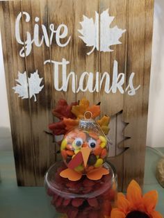 a turkey ornament sitting on top of a table next to flowers and a sign