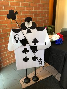 a table with a black and white playing card costume on it's legs, standing next to a brick wall