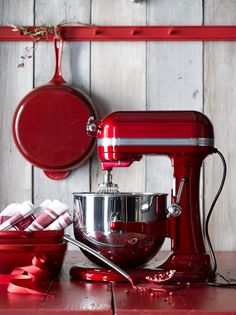 a red mixer sitting on top of a wooden table