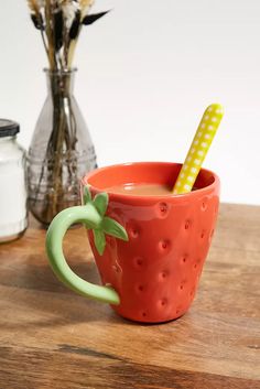 a red cup with a straw in it sitting on a table next to some flowers