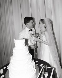 a bride and groom are about to cut their wedding cake at the reception table in black and white