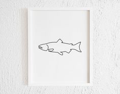 a black and white drawing of a fish in a frame on the wall above it