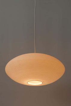 a white light hanging from the ceiling in a room with grey walls and flooring