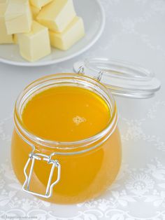 a glass jar filled with liquid sitting on top of a table next to sliced cheese