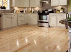 a large kitchen with white cabinets and stainless steel appliances, wood flooring and an island in the middle