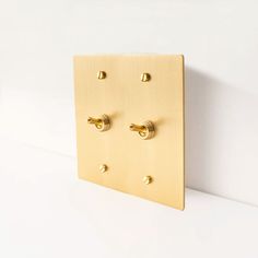 a wall mounted light switch plate with four brass knobs on the front and sides