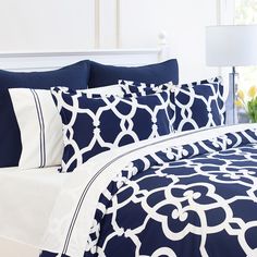 a bed with blue and white comforters, pillows and lamps on the nightstands