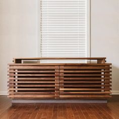 a wooden cabinet sitting on top of a hard wood floor in front of a window