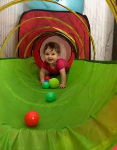 a small child playing with balls in a play tunnel