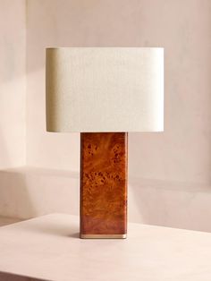 a table lamp sitting on top of a white counter next to a wall and window