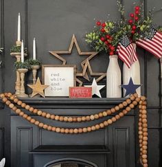 a fireplace with decorations on it and candles in front of the fire place, including an american flag garland