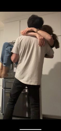 two people hug in the kitchen while standing next to an oven