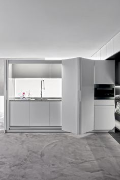 a kitchen with white cabinets and black counter tops in an open space that has no people around it