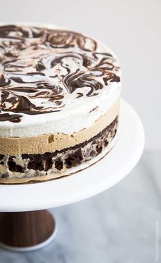 a cake with chocolate and cream frosting sitting on a white plate next to a wooden spatula