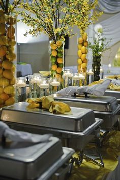 there are many vases with yellow flowers and candles on the table in front of them