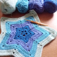 a crocheted star is sitting on a table next to balls of yarn and knitting needles