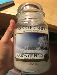 a person holding a jar of yankee candle