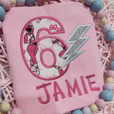 a pink birthday shirt with the number sixty and lightning bolt on it, surrounded by candy