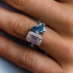 a woman's hand with a blue and white diamond ring on her left hand