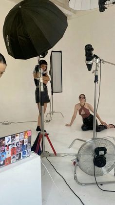 two women are sitting on the floor in front of an umbrella and several other equipment