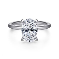 an oval cut diamond engagement ring on a white background