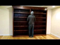 a man standing in front of a bookcase with his back turned to the camera