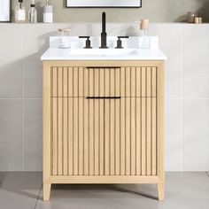 a bathroom vanity with two sinks and a mirror on the wall above it, in front of a white tiled wall