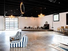 an empty room with chairs, tables and chandeliers hanging from the ceiling in front of a flat screen tv