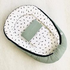 a green and white baby bed with black birds on it's cover, sitting on the floor