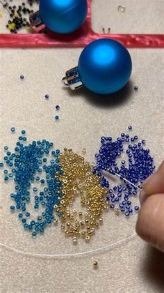 someone is making beaded ornaments on a piece of paper with scissors and beads in front of them