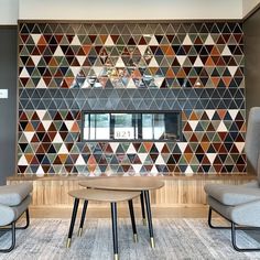 a room with two chairs and a table in front of a wall that has geometric tiles on it