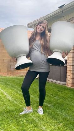 a pregnant woman holding two large lamps in her hands