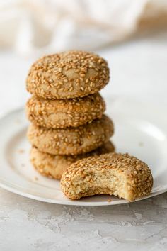 three sesame seed cookies stacked on top of each other in a white plate with a bite taken out