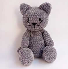 a gray crocheted teddy bear sitting up against a white background