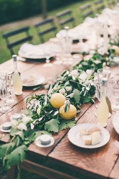 the table is set with lemons and greenery