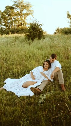 a man and woman are laying in the grass with their arms wrapped around each other