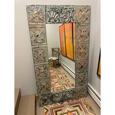 an ornately decorated mirror in the corner of a room with a chair and rug on the floor