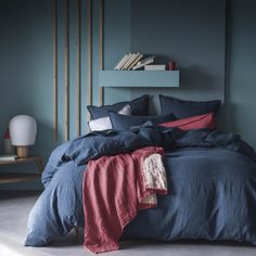 a bed with blue sheets and red pillows