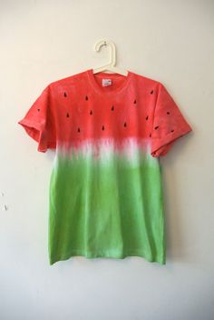 a watermelon t - shirt hanging on a white wall with a hanger