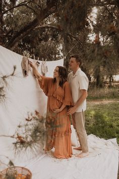 a man and woman standing next to each other in front of clothes hanging on a line