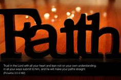 the word faith is placed on top of a wooden table with candles in the background