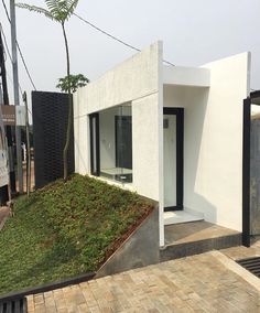 a white house with grass on the roof and side walk leading up to it's entrance