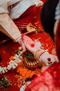 the bride and grooms hands are covered with red dye as they sit on their wedding day