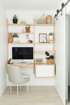 a home office with shelving, shelves and a computer on a desk in front of a white wall