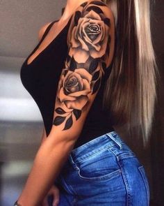 a woman with long hair wearing a black top and roses tattoo on her arm,