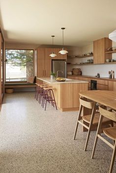 an open kitchen and dining area with wooden cabinets, counter tops, and stools